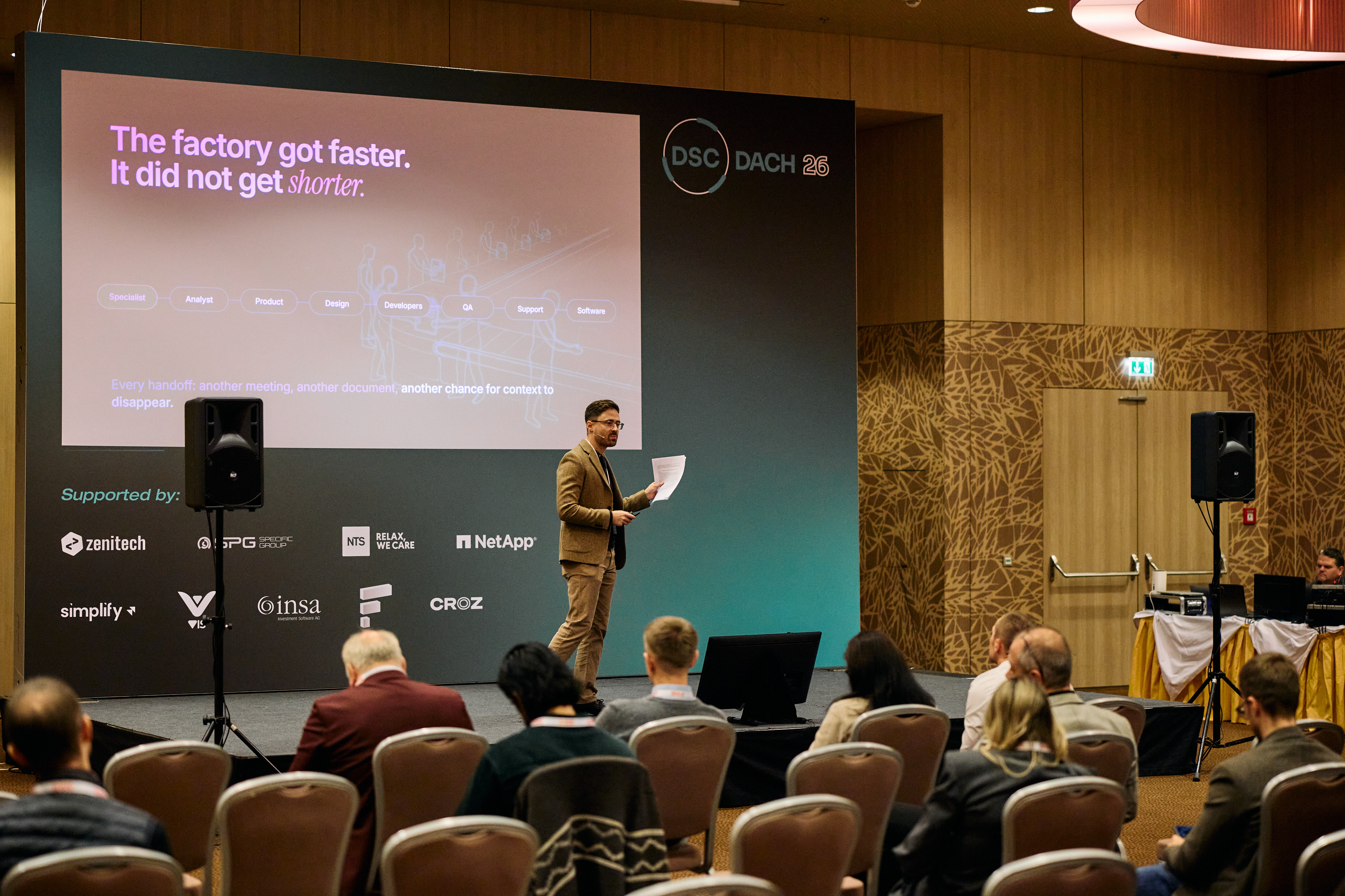 A wider audience view of Daniil and the software-factory slide on stage